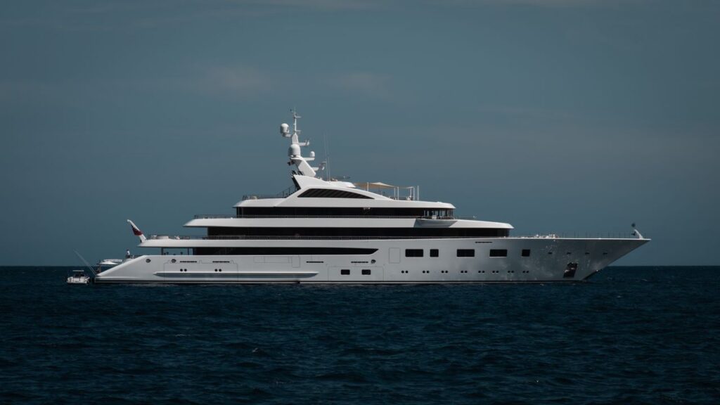 A sleek luxury yacht cruising on the calm open ocean under a clear sky.